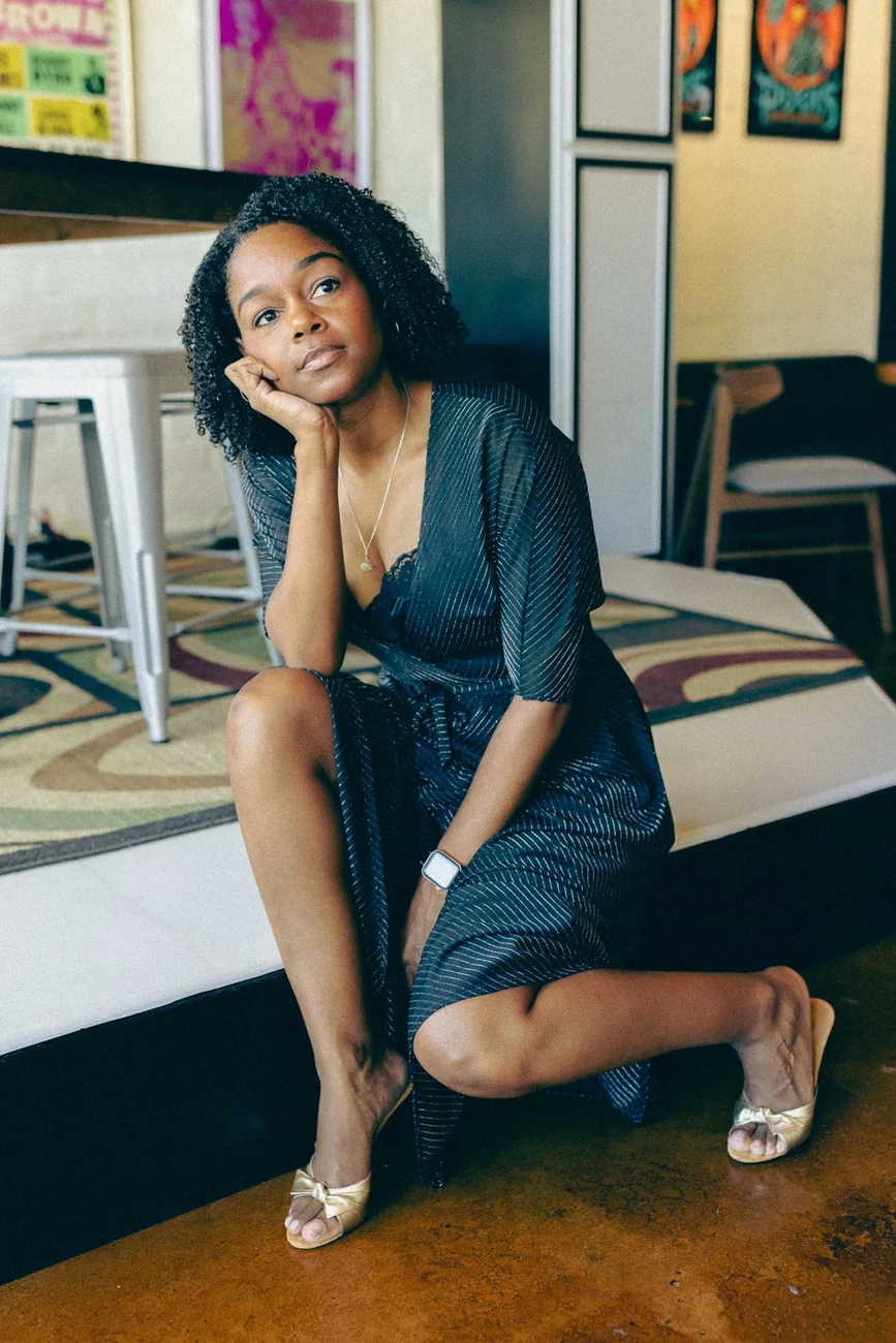 Shante seated in a dark wrap dress
